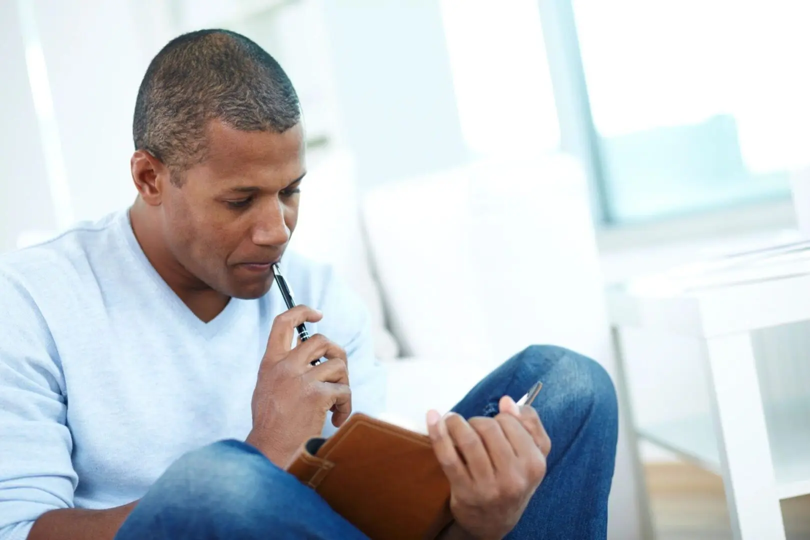 A man holding a diary and pen and thinking